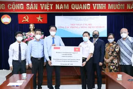 Ông Nguyễn Thành Trung, Phó Chủ tịch Ủy ban Mặt trận Tổ quốc Việt Nam Thành phố Hồ Chí Minh (thứ 3 từ trái sang) tiếp nhận tượng trưng số tiền và hàng hóa do doanh nghiệp và cộng đồng người Indonesia trao tặng. (Ảnh: Xuân Khu/TTXVN)