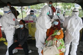 Nhân viên y tế lấy mẫu xét nghiệm COVID-19 cho người dân tại Surabaya, Đông Java, Indonesia. (Ảnh: THX/TTXVN)