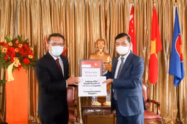 Đại sứ Việt Nam tại Singapore Mai Phước Dũng (phải) tiếp nhấn tượng trưng lô hàng do Quỹ Temasek trao tặng. (Ảnh: Lê Dương/TTXVN)