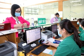 Người dân sử dụng ứng dụng VssID thay thế thẻ bảo hiểm giấy khi đăng ký khám bệnh. (Ảnh: Hữu Quyết/TTXVN)