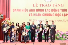 Chủ tịch nước Nguyễn Xuân Phúc tặng chân dung Chủ tịch Hồ Chí Minh cho đại diện gia đình và các cá nhân tại buổi lễ. (Ảnh: Thống Nhất/TTXVN)