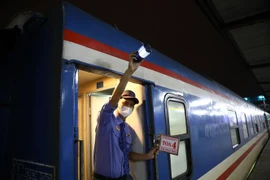 Nhân viên đường sắt hiệu lệnh tàu bắt đầu lăn bánh. (Ảnh: Huy Hùng/TTXVN)