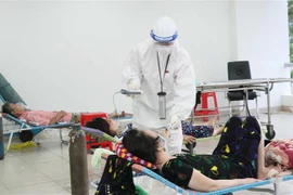 Các bác sỹ thăm khám bệnh nhân nhiễm COVID-19 không triệu chứng có bệnh nền. (Ảnh: Xuân Khu/TTXVN)
