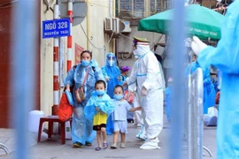 Trẻ em ở Thanh Xuân Trung theo gia đình di chuyển đến khu cách ly. (Ảnh: Tuấn Anh/TTXVN)