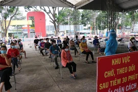 Người dân ngồi xếp hàng để được tiêm vaccine Vero Cell tại điểm tiêm Trung tâm văn hóa phường Phú Lợi, thành phố Thủ Dầu Một, tỉnh Bình Dương. (Ảnh: Chí Tưởng/TTXVN)