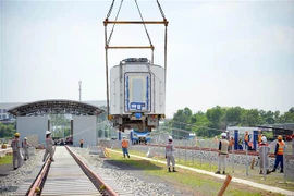 Công tác lắp đặt toa xe đầu tiên của đoàn tàu số 2 lên đường ray tại depot. (Ảnh: Tiến Lực/TTXVN)