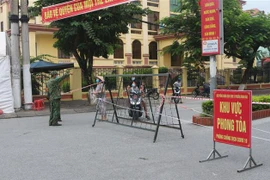 Lực lượng chức năng hướng dẫn người dân không đi ra khỏi khu vực phong tỏa. (Ảnh: Thanh Tuấn/TTXVN)
