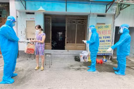 Nhân viên y tế trạm y tế lưu động phường 25, quận Bình Thạnh phát túi thuốc cho F0 điều trị tại nhà. (Ảnh: Đinh Hằng/TTXVN)