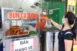 Từ 6h20, một quán bún cá trên phố Mai Hắc Đế đã có khách mua mang về. (Ảnh: Hoàng Hiếu/TTXVN)