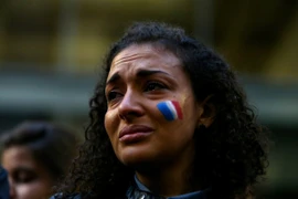 Một phụ nữ vẽ hình quốc kỳ Pháp trên mặt trong buổi lễ cầu nguyện cho các nạn nhân trong 6 vụ tấn công khủng bố Paris tổ chức tại cung điện Martin, Sydney, Australia. (Ảnh: Getty)