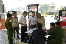 Lực lượng chức năng lập biên bản một cây xăng có gắn chíp gian lận. (Ảnh: TTXVN)