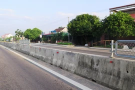 Một đoạn dải phân cách cứng trên Quốc lộ 1A bị người dân tháo dỡ để làm lối băng qua đường. (Ảnh: TTXVN)