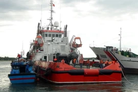 Tàu cảnh sát biển lai dắt một tàu cá gặp nạn vào bờ. (Ảnh: Đỗ Trưởng/TTXVN)