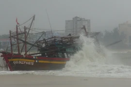 Một tàu cá bị mắc cạn, có nguy cơ bị sóng đánh chìm tại cửa biển Nhật Lệ, thành phố Đồng Hới, tỉnh Quảng Bình. (Ảnh: TTXVN)