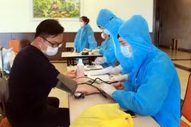 Nhân viên y tế hướng dẫn chuyên gia, lao động nước ngoài khai báo y tế và kiểm tra sức khỏe trước khi vào khách sạn cách ly. (Ảnh: TTXVN)