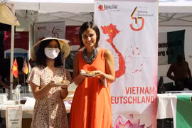 Phó Thị trưởng thành phố Augsburg, bà Martina Wild (áo dài cam), ấn tượng với ẩm thực của Việt Nam. (Ảnh: TTXVN phát)