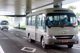 Hành khách xuống sân bay Vân Đồn được lên ôtô chở về khu cách lý theo quy định. (Ảnh: TTXVN)