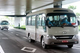 Hành khách xuống sân bay Vân Đồn được lên ôtô chở về khu cách lý theo quy định. (Ảnh: TTXVN)