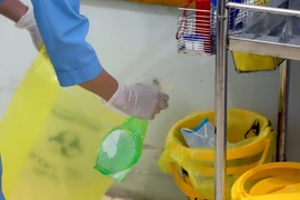 Nhân viên y tế Trung tâm y tế huyện Bình Xuyên xịt dung dịch sát khuẩn vào thùng lưu chứa chất thải trước khi để vào nơi quy định. (Ảnh: Hoàng Hùng/TTXVN)