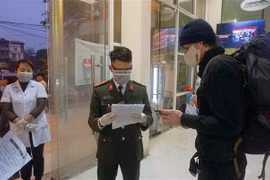 Du khách người nước ngoài phải đối chiếu tờ khai y tế với hộ chiếu khi xuống tàu ở Ga Lào Cai. (Ảnh: Quốc Khánh/TTXVN)