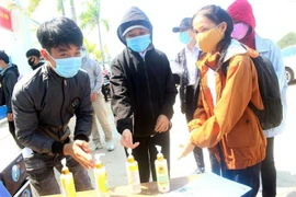 Các thí sinh đều nghiêm túc rửa tay bằng dung dịch sát khuẩn trước khi vào làm thủ tục thi. (Ảnh: Trịnh Bang Nhiệm/TTXVN)