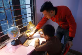 Phụ huynh hỗ trợ học sinh lớp 3 trường Tiểu học Hoàng Lê, thành phố Hưng Yên học trực tuyến tại nhà. (Ảnh: Phạm Kiên/TTXVN)