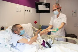 Nhân viên y tế tặng hoa hồng và sách cho bệnh nhân nhiễm COVID-19 tại bệnh viện ở Barcelona, Tây Ban Nha, ngày 23/4/2020. (Ảnh: THX/TTXVN)