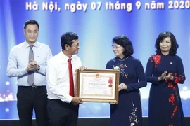 Phó Chủ tịch nước Đặng Thị Ngọc Thịnh, Phó Chủ tịch thứ nhất Hội đồng Thi đua-Khen thưởng Trung ương trao Huân chương Lao động hạng Nhất của Chủ tịch nước cho tập thể Đài Truyền hình Việt Nam. (Ảnh: Dương Giang/TTXVN)