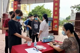 Thí sinh được đo thân nhiệt, rửa tay sát khuẩn trước khi vào làm thủ tục dự thi. (Ảnh: Xuân Thỏa/TTXVN)