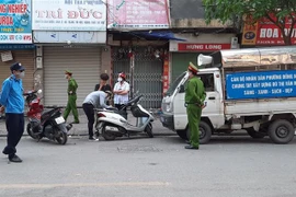 Tổ công tác phường Đồng Nhân (quận Hai Bà Trưng, Hà Nội) xử phạt các trường hợp vi phạm không đeo khẩu trang ra đường. (Ảnh: Doãn Tấn/TTXVN)