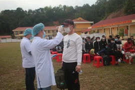 Đo thân nhiệt cho các công dân trước khi rời khỏi khu cách ly tập trung. (Ảnh: Chu Hiệu/TTXVN)