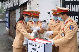 Cảnh sát giao thông chuẩn bị khẩu trang phát miễn phí cho người tham gia giao thông phòng chống dịch. (Ảnh: PV/Vietnam+)