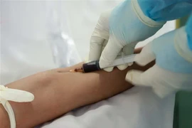 Kỹ thuật viên lấy mẫu máu bệnh nhân làm xét nghiệm. (Ảnh: Hoàng Hùng/TTXVN)