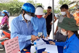 Người dân tự nguyện đến hỗ trợ tiền, gạo. (Ảnh: Đức Hạnh/TTXVN)