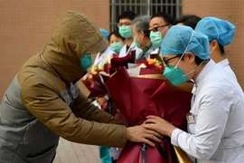 Một bệnh nhân (trái) tri ân các nhân viên y tế sau khi được chữa khỏi bệnh viêm đường hô hấp cấp do nhiễm virus corona chủng mới tại một bệnh viện ở Thiểm Tây, Trung Quốc ngày 4/2/2020. (Ảnh: THX/TTXVN)