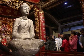 Nhân dân đến lễ trước bảo vật quốc gia Tượng phật A di đà bằng đá tại chùa Phật Tích. (Ảnh: Thanh Thương/TTXVN)
