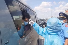 Nhân viên y tế đo thân nhiệt người ra vào Thành phố Hồ Chí Minh tại chốt kiểm dịch. (Ảnh: Đinh Hằng/TTXVN)