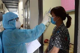 Kiểm tra thân nhiệt cho người dân. (Ảnh minh họa: Quốc Dũng/TTXVN)