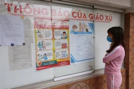 Một giáo dân xem các thông tin về dịch COVID-19. (Nguồn: TTXVN)