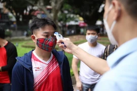 Kiểm tra thân nhiệt cho khách vào thăm quan Di tích lịch sử Văn Miếu-Quốc Tử Giám. (Ảnh: Thành Đạt/TTXVN)