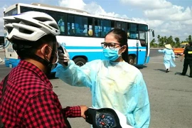 Lực lượng chức năng ở Cần Thơ thực hiện đo thân nhiệt tại các điểm giám sát y tế trên địa bàn. (Ảnh: Ánh Tuyết/TTXVN)