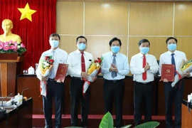 Ông Nguyễn Hoàng Thao (người thứ ba bên phải qua) - Phó Bí thư Thường trực Tỉnh ủy; ông Trần Thanh Liêm (thứ hai bên phải qua), Chủ tịch UBND tỉnh trao quyết định và tặng hoa cho các cán bộ chủ chốt được điều động, bổ nhiệm. (Ảnh: Nguyễn Văn Việt/TTXVN)