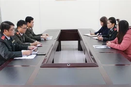 Lực lượng chức năng làm việc với người đăng thông tin sai sự thật (áo hồng) tại Sở Thông tin và Truyền thông tỉnh Phú Thọ. (Ảnh: Trung Kiên/TTXVN)