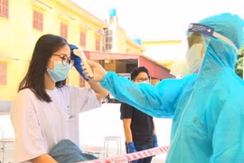 Bác sỹ kiểm tra thân nhiệt cho công dân. (Ảnh: Đinh Tuấn/TTXVN)
