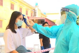 Bác sỹ kiểm tra thân nhiệt cho công dân. (Ảnh: Đinh Tuấn/TTXVN)