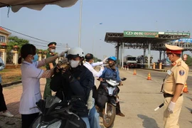 Lực lượng chức năng đo thân nhiệt các lái xe môtô đi vào địa bàn tỉnh Đắk Nông. (Ảnh: Ngọc Minh/TTXVN)