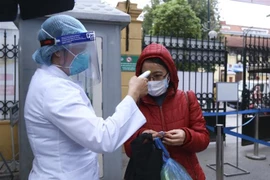 Kiểm tra thân nhiệt với người vào bệnh viện. (Nguồn: TTXVN)