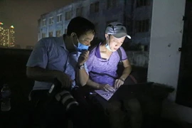 Phóng viên ảnh của TTXVN xử lý, truyền phát ảnh ngay trong đêm tại hiện trường vụ cháy nhà máy của Công ty CP Bóng đèn phích nước Rạng Đông (Hà Nội), tháng 8/2019. (Ảnh: Thành Đạt/TTXVN)