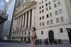 Người dân Mỹ đeo khẩu trang phòng chống COVID-19 khi đi bên ngoài Sàn giao dịch chứng khoán New York. (Ảnh: THX/TTXVN)