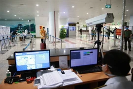 Lực lượng y tế kiểm tra thân nhiệt đối với hành khách nhập cảnh. (Ảnh: Doãn Tấn/TTXVN)